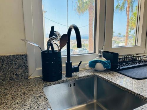 a kitchen sink with utensils in a container next to a window at Smart Apartments Tarifa, Parking facil y aire acondicionado in Tarifa