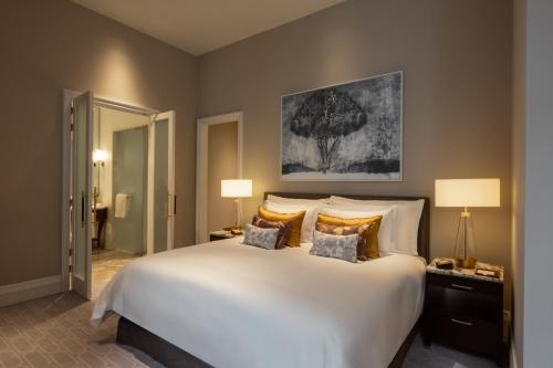 a bedroom with a large white bed and two lamps at Corinthia Grand Hotel Astoria Brussels in Brussels