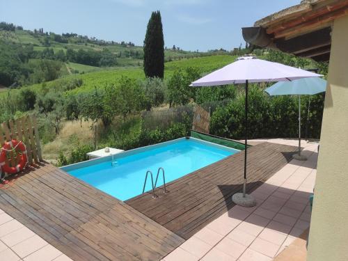 a pool with a wooden deck and an umbrella at Farmhouse in Tuscany with Pool & Vineyard View in Lucardo