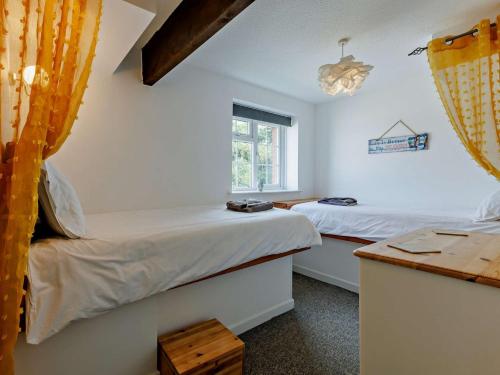 Un dormitorio con dos camas y un escritorio y una ventana. en 4 Bed in Westward Ho 46838, en Westward Ho