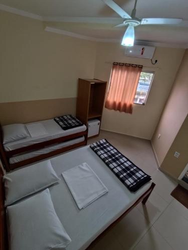 a bedroom with two beds and a ceiling fan at Pousada São Miguel Arcanjo in Aparecida