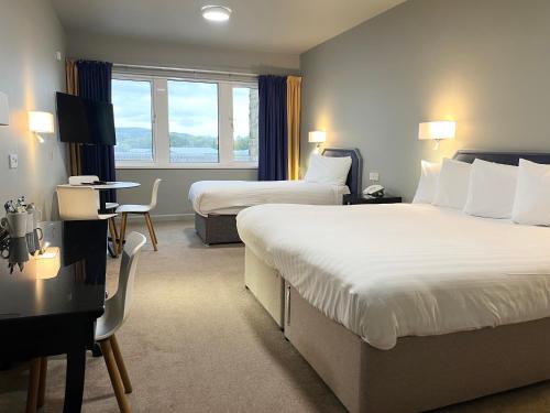 a hotel room with two beds and a desk at Skipton Hotel - formerly known as Hotel Rendezvous-Skipton in Skipton
