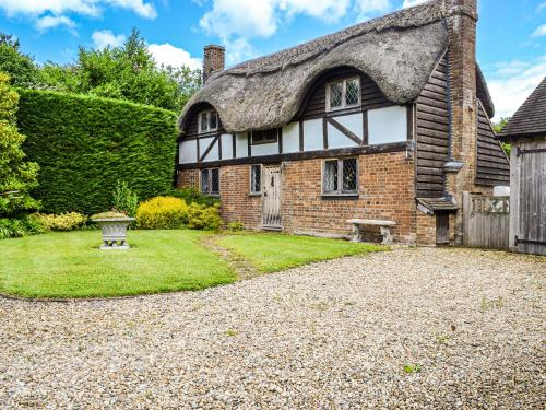 an old house with a thatched roof and a gravel driveway at The Old Thatched Cottage in Tenterden