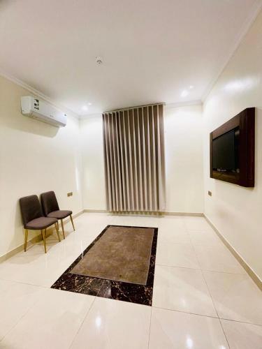 a living room with two chairs and a television at الاندلس الشريبات in Al Madinah