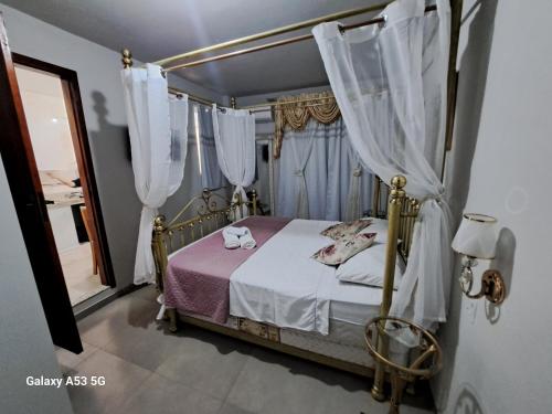 a bedroom with a canopy bed with white curtains at Lindo apartamento centro barra mansa in Barra Mansa
