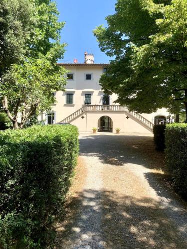 a large white house with a driveway and trees at Appartamento in villa storica: Villa Giulia in Empoli