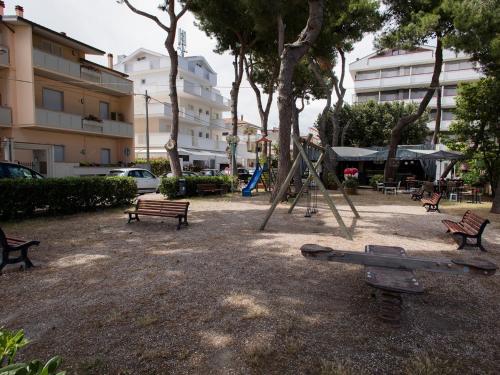 a playground with benches and a swing set in a park at Manè Boutique Hotel in Roseto degli Abruzzi