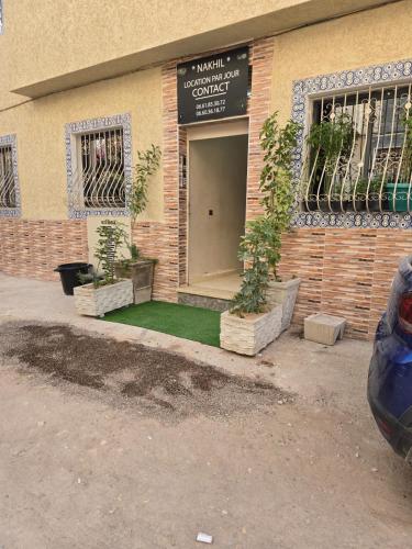 a building with two potted plants in front of a door at Immeuble ANAKHIL appartement surf in Tamraght Ouzdar