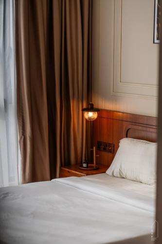 a bedroom with a bed and a lamp next to a window at The M Medini Macrolink by Cactus Homestay in Iskandar Puteri
