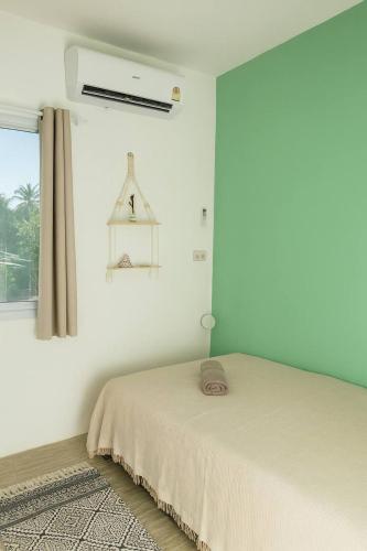 a white bedroom with a bed and a window at Unity Guest House in Thong Sala