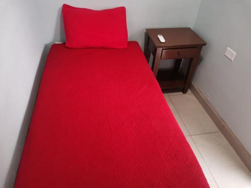 a red bed with a red pillow and a table at Rocky Point Casa Mango w Pool Walk to Beach in Ciudad Constitución