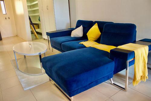 a blue couch with yellow pillows in a living room at Elroiairbnb in Amanzimtoti
