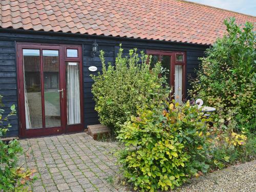 a black house with a red roof and some bushes at Oregano - E4483 in Ludham