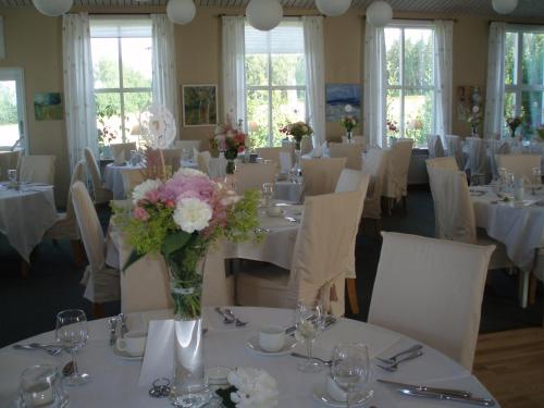 a dining room with white tables and chairs with flowers in a vase at Åkerby Herrgård in Nora