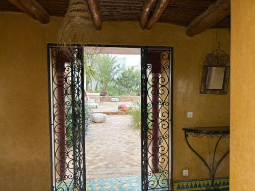 an open door to a yard with a patio at Riad TAWALA Surfing Mind in Tamraght Ouzdar