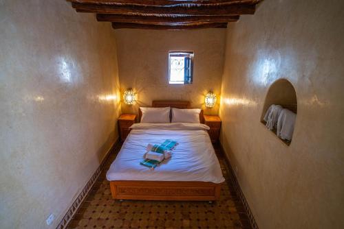 a small bedroom with a bed with a towel on it at Riad TAWALA Surfing Mind in Tamraght Ouzdar
