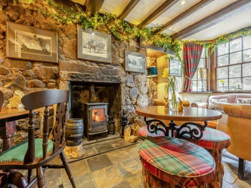 a living room with a stone fireplace and a table and chairs at Tormaukin House in Glendevon