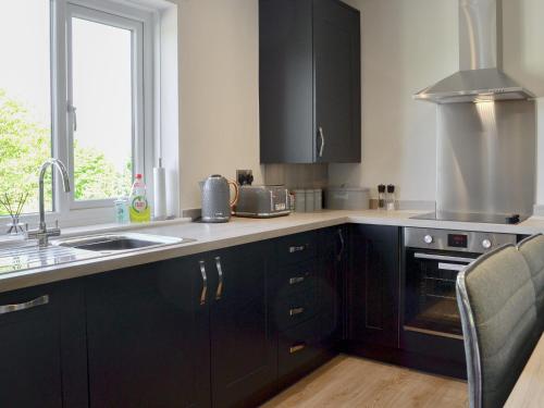 a kitchen with black cabinets and a sink and a window at Kestrel View in Skipton