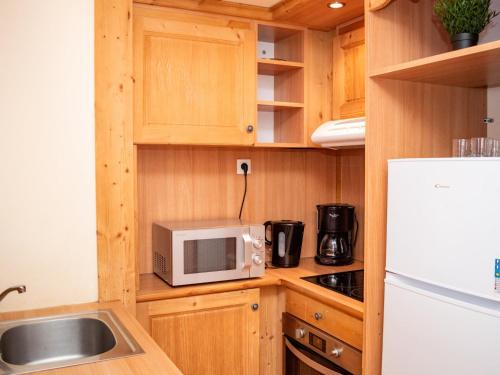 a small kitchen with wooden cabinets and a white microwave at Appartement cosy 2 pièces à Pra Loup avec balcon et parking - FR-1-504-231 in Uvernet-Fours