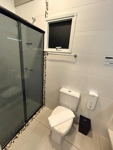 a bathroom with a toilet and a shower and a window at Hotel Locatelli in Lajeado