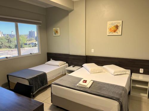 a hotel room with two beds and a window at Hotel Locatelli in Lajeado