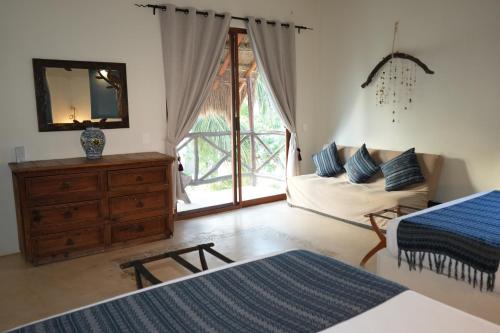 a bedroom with a bed and a dresser and a mirror at Hotel Boutique La Puerta Azul Beachfront - Adults Only in Holbox Island