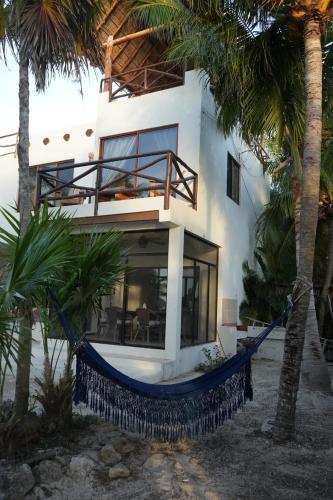 a hammock in front of a house with palm trees at Hotel Boutique La Puerta Azul Beachfront - Adults Only in Holbox Island