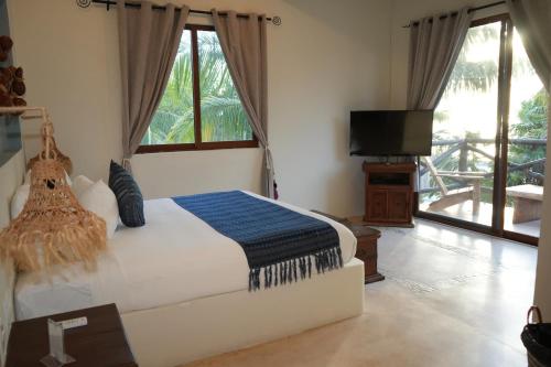 a bedroom with a bed and a flat screen tv at Hotel Boutique La Puerta Azul Beachfront - Adults Only in Holbox Island