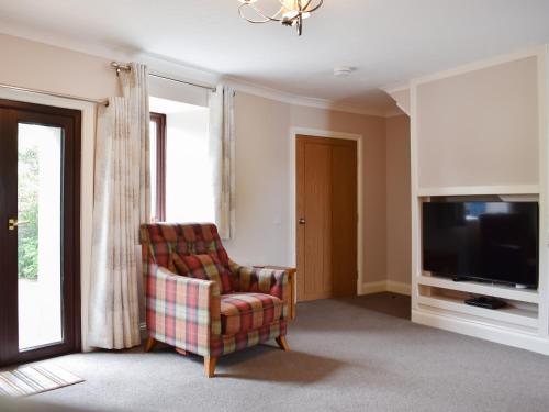 a living room with a chair and a television at The Martins - Uk47429 in Bewaldeth