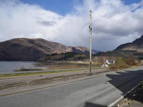 an empty road next to a body of water and mountains at Quarter Deck Gardens in Glencoe
