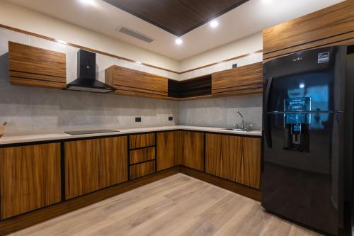 a kitchen with wooden cabinets and a black refrigerator at Hotel Mundo Maya Tulum Aeropuerto in Tulum