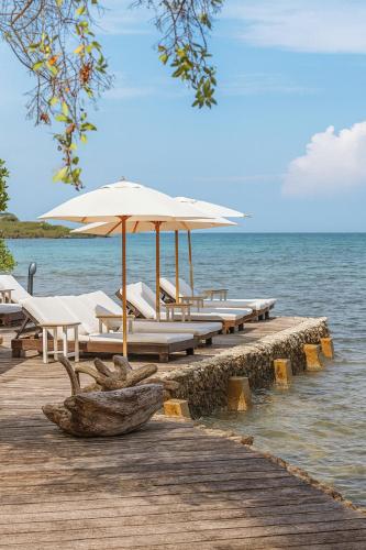a dock with chairs and umbrellas on the water at Fragata Island House in Isla Grande
