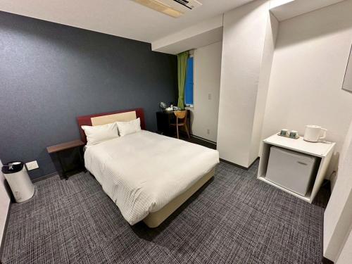 a small bedroom with a bed and a table at Grampus Inn Osaka Namba in Osaka
