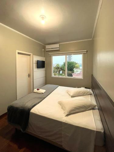 a bedroom with a large bed with a window at Hotel Locatelli in Lajeado
