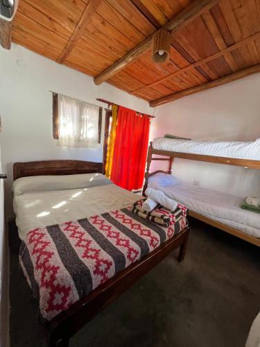 two beds in a room with a red curtain at Hostal Tierra Andina Cafayate in Cafayate