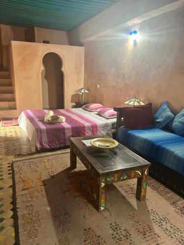 a room with two beds and a table and a couch at Riad Felloussia in Meknès