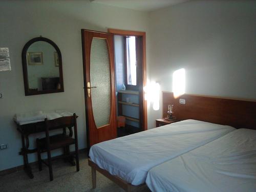 Un dormitorio con una cama, un escritorio y un espejo. en B&B 'Tra i due Parchi'', en Avezzano