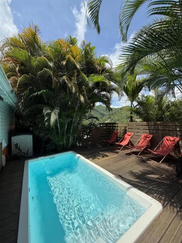 a swimming pool in a yard with chairs and palm trees at Villa Ti Gîte - Piscine privée in Le Marin