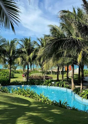 a resort with a swimming pool with palm trees at K' SEA VIEW ARENA RESORT o in Miếu Ông