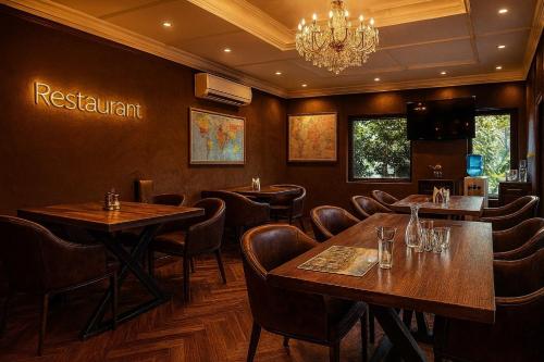 a restaurant with tables and chairs and a chandelier at The Vrindavan Manor - A Boutique Wellness Resort in Lap of Nature # By Elegance Group # in Vrindāvan