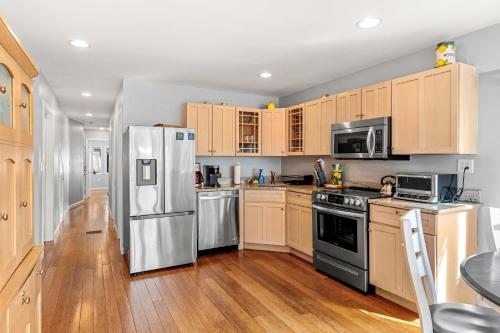 a kitchen with stainless steel appliances and wooden cabinets at Serendipity Beach Retreat Nautical Retreat in Salisbury Beach