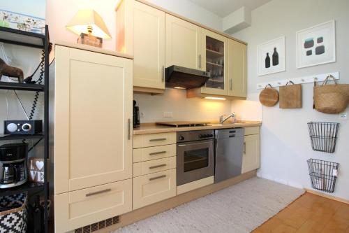 a kitchen with white cabinets and stainless steel appliances at Am Grün 15 Fewo 25 in Wittenbeck
