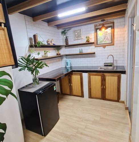 a kitchen with a black refrigerator and wooden cabinets at TỊNH Retreat Phu Quoc in Phu Quoc