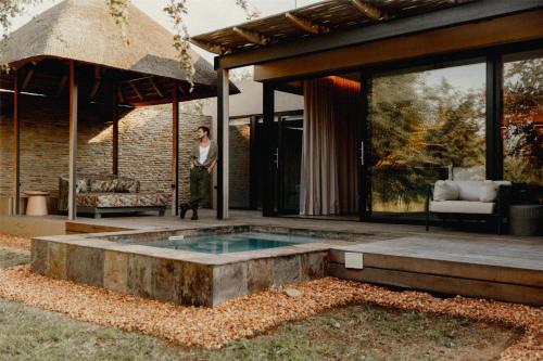 a woman standing in front of a house with a pool at Radisson Safari Hotel Hoedspruit in Hoedspruit