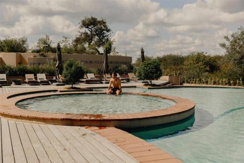 a man sitting in a pool in a swimming pool at Radisson Safari Hotel Hoedspruit in Hoedspruit