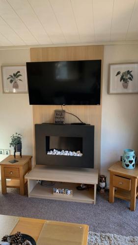 a living room with a flat screen tv above a fireplace at Ednas Lodge in Wisbech