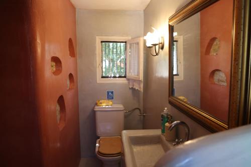 ein Badezimmer mit Toilette, Waschbecken und Spiegel in der Unterkunft Traditional cottage house in front of the beach in Ríva