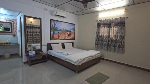 a bedroom with a bed and a painting on the wall at The Wilds Villa Gir Jungle Stay with Swimming Pool in Sasan Gir