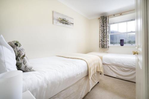 a white bedroom with two beds and a window at The Screes - Short stroll from Wastwater in Nether Wasdale