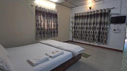 a bedroom with two beds and a tv and curtains at The Wilds Villa Gir Jungle Stay with Swimming Pool in Sasan Gir
